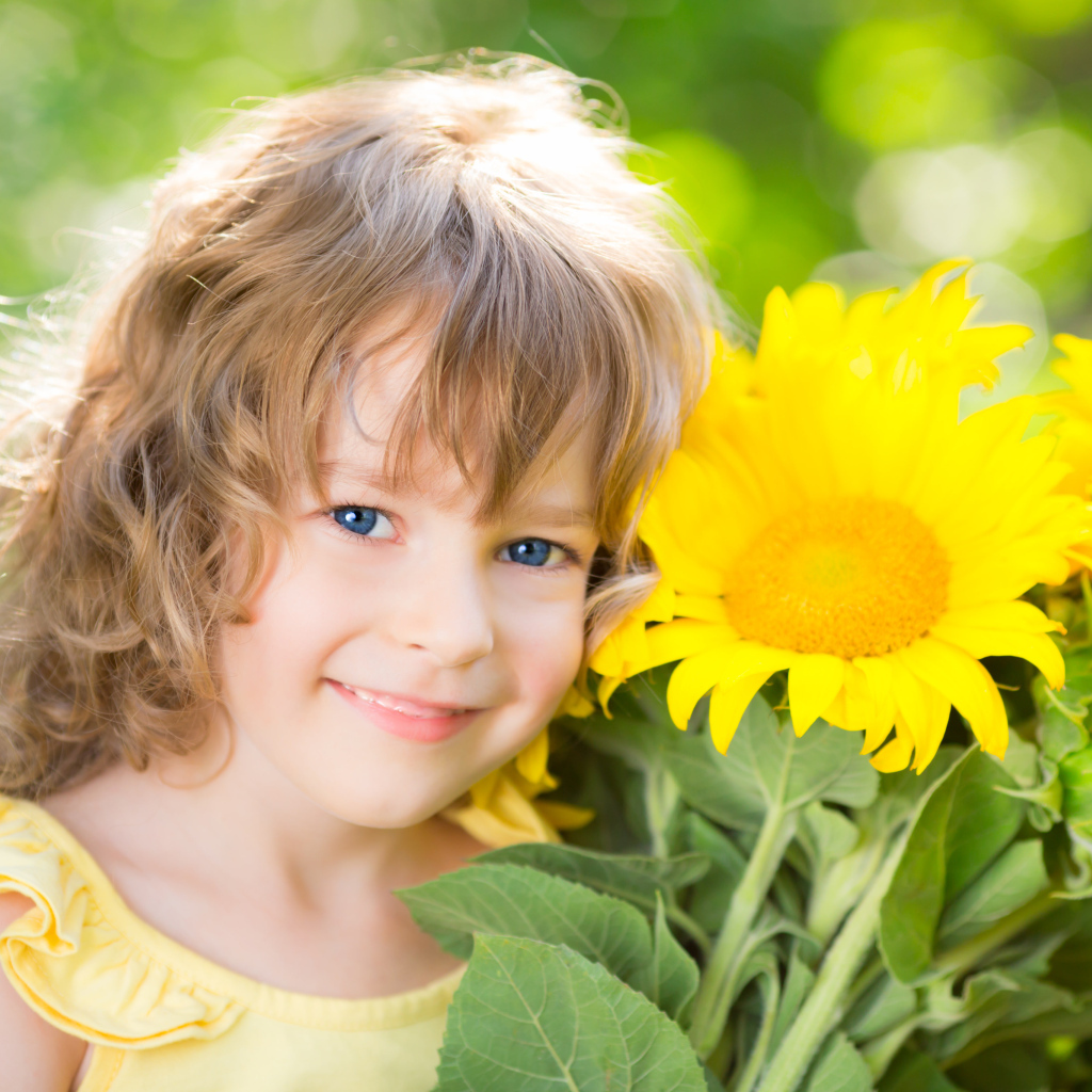 Красивая голубоглазая девочка с букетом подсолнухов