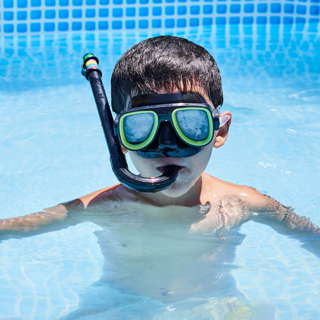 Мальчик в маске сидит в плавательном бассейне