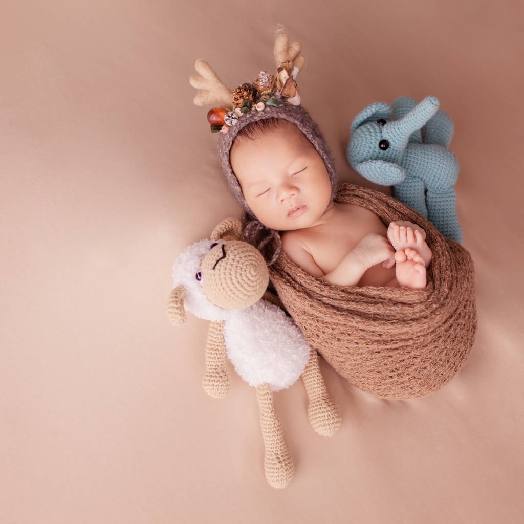 Маленький ребенок в костюме оленя с игрушкой