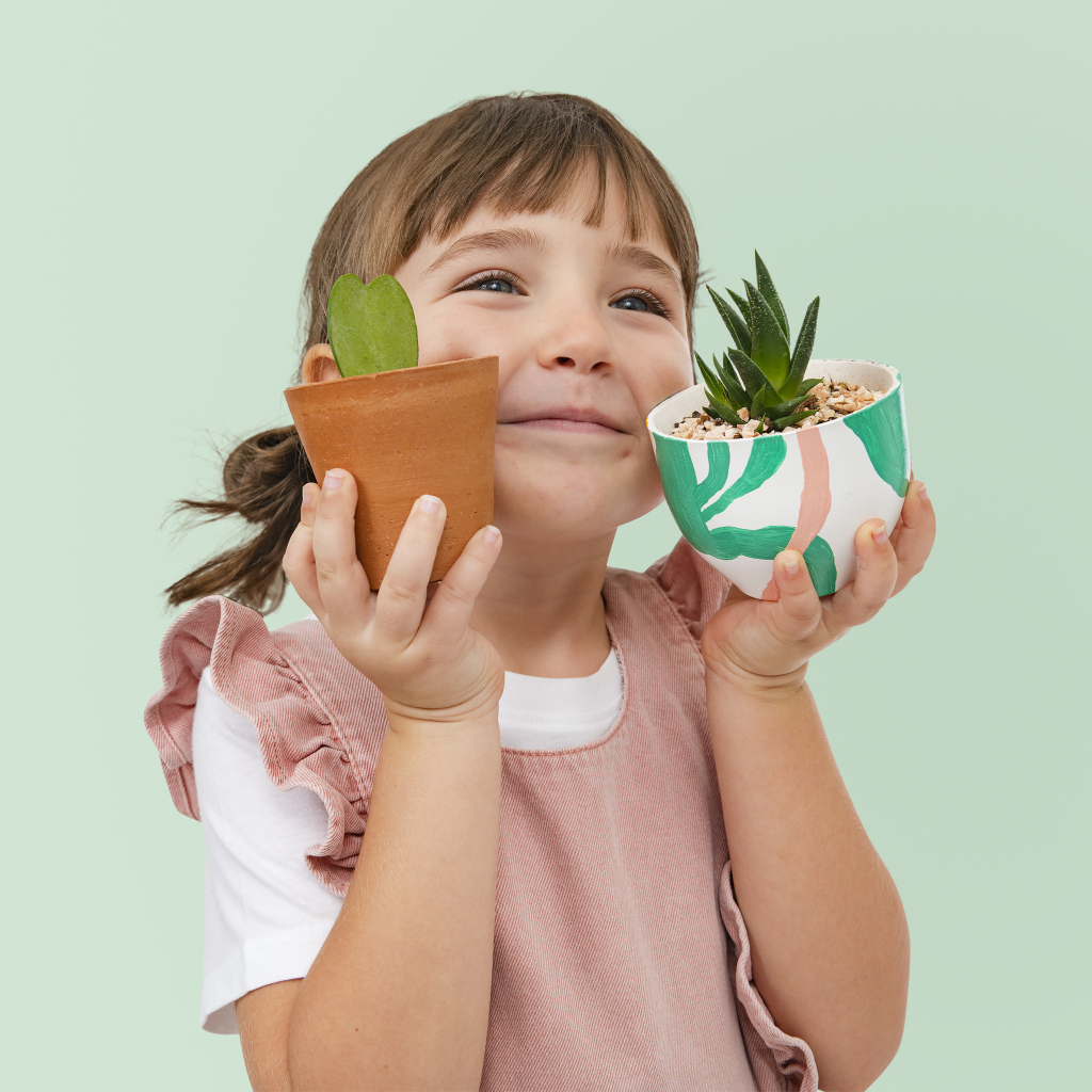 Маленькая девочка с комнатными цветами в руках