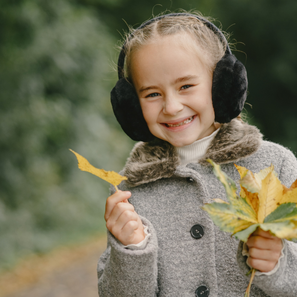 Улыбающаяся девочка с опавшими листьями в руках
