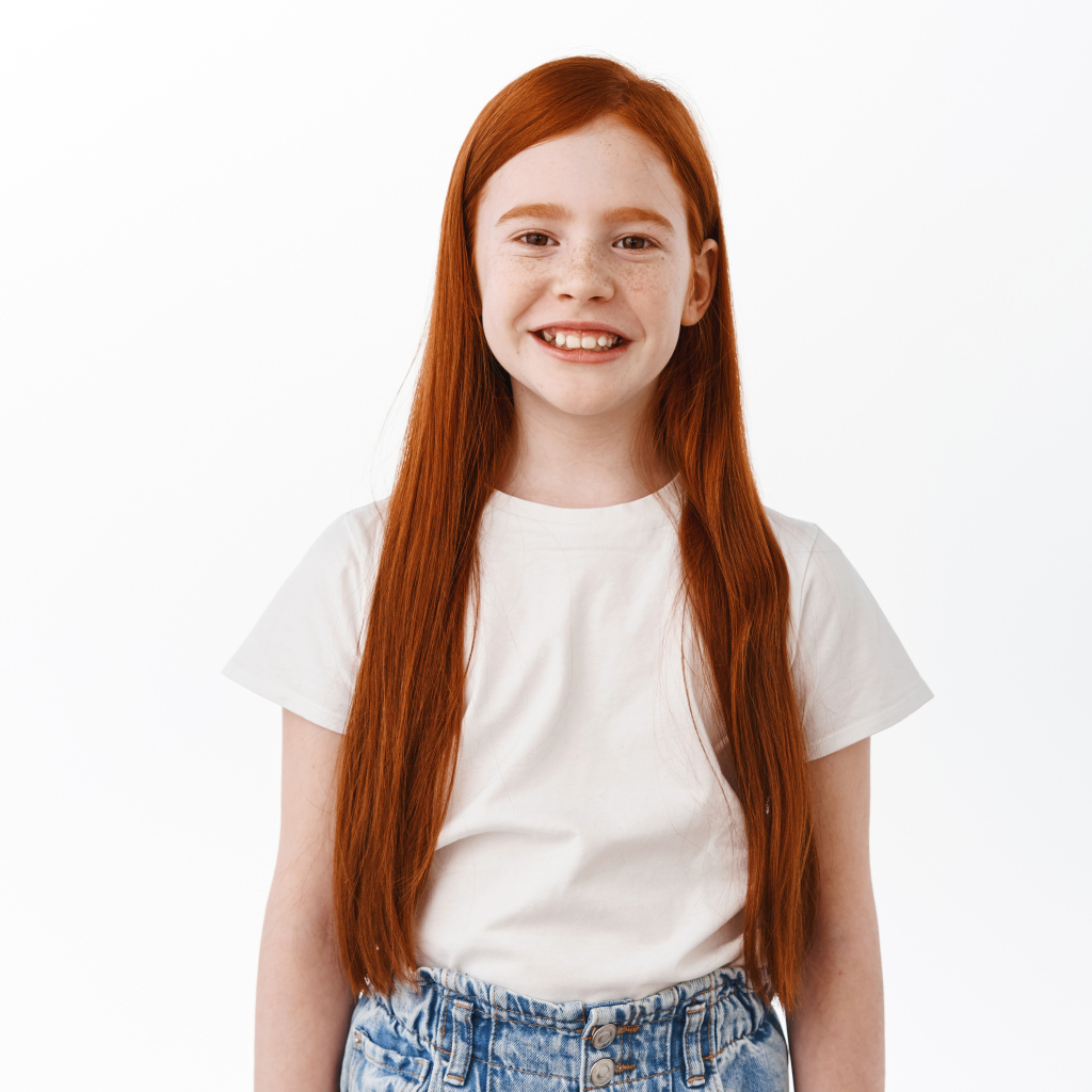 Улыбающаяся рыжеволосая девочка на белом фоне