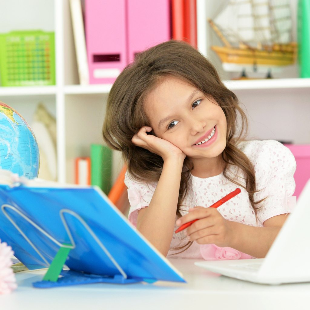 Улыбающаяся школьница делает уроки