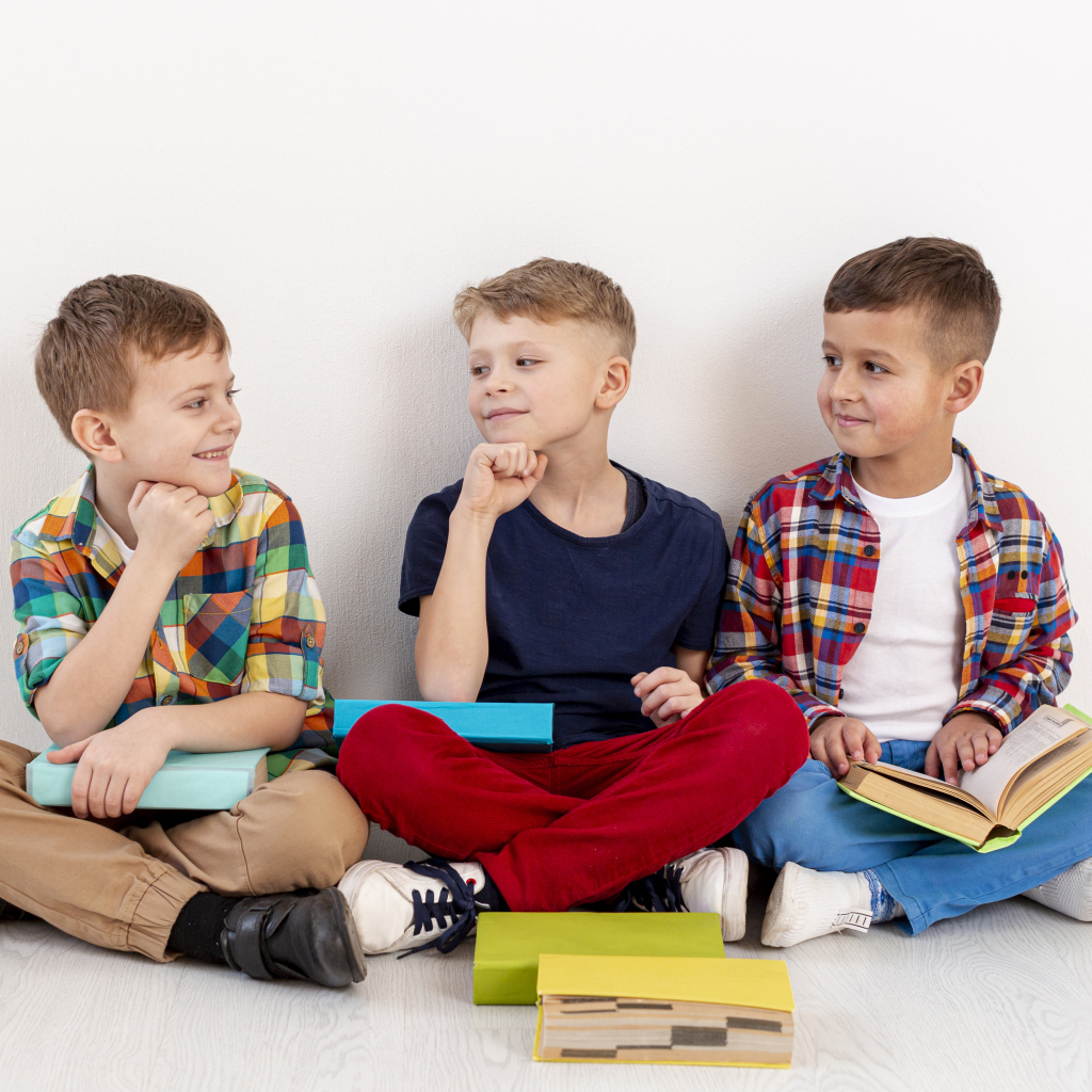 Три мальчика с книгами сидят у стены