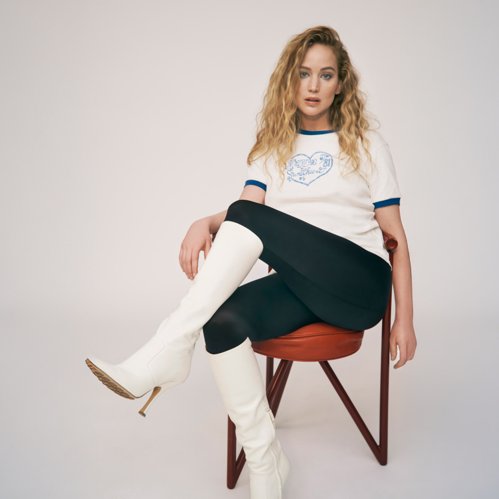 Актриса Дженнифер Лоуренс сидит на стуле на сером фоне