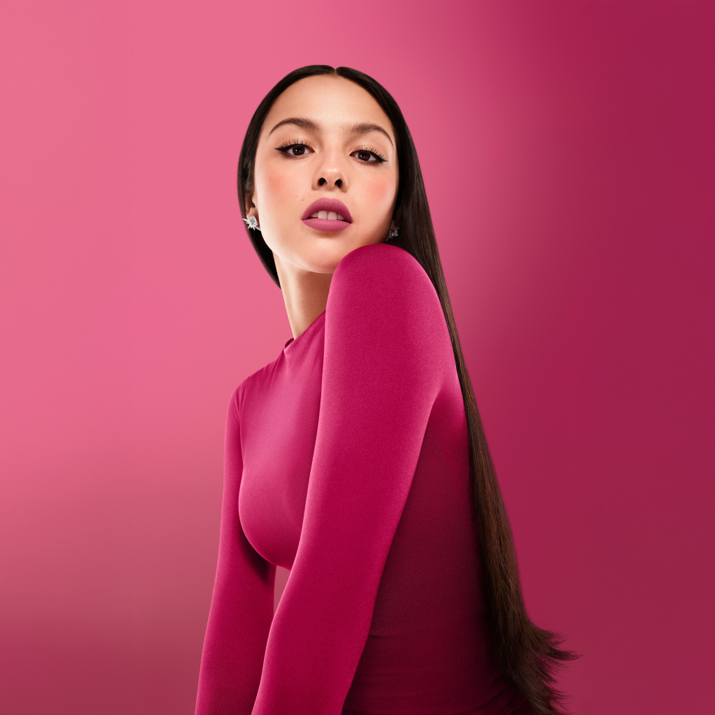 Длинноволосая актриса Оливия Родриго на розовом фоне