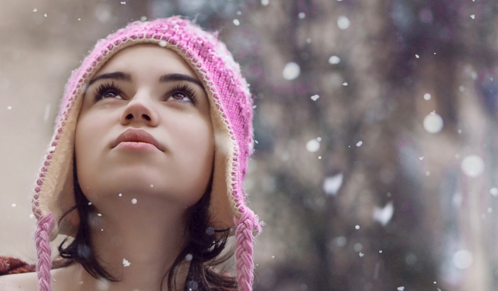 Девушка смотрит на падающий снег
