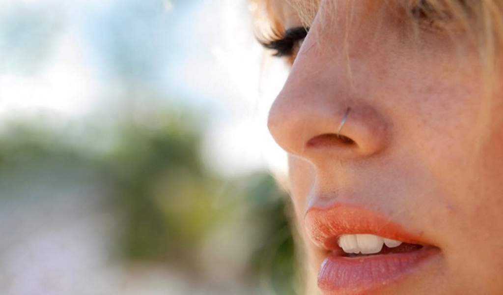 Девушка блондинка с пирсингом в носу крупным планом