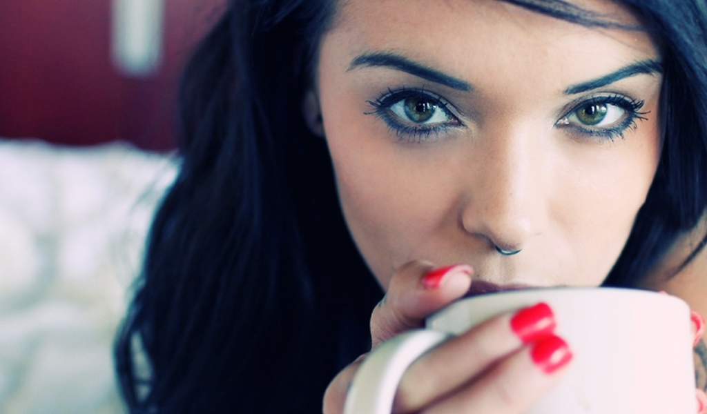 Девушка брюнетка с пирсингом в носу и красными ногтями