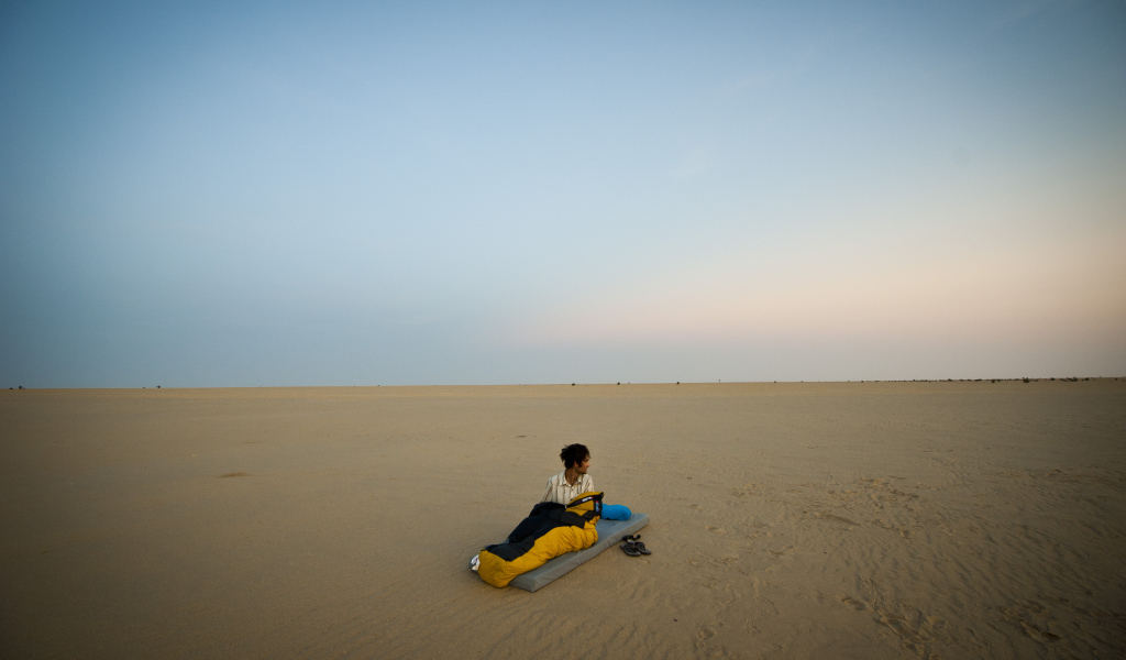 Мужчина на матрасе на пляже