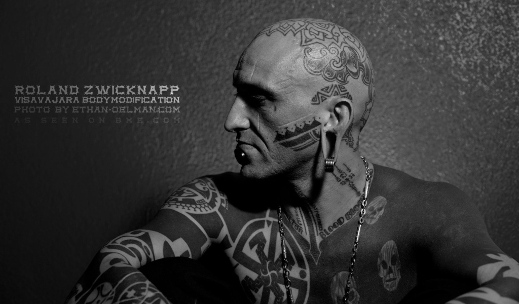 Мужчина с пирсингом в губе и татуировками