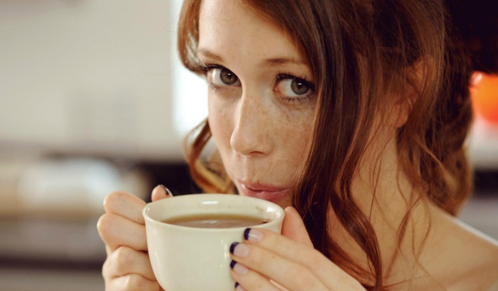 Девушка с веснушками пьет кофе