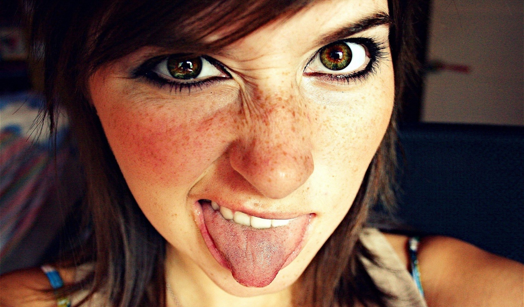 Девушка с веснушками показывает язык