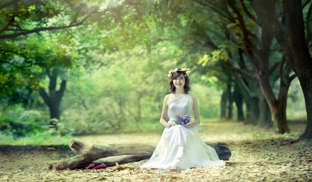 Девушка сидит на бревне