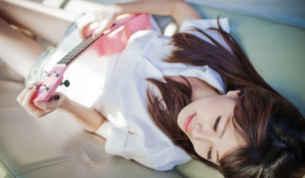 Брюнетка и розовая гитара на диване