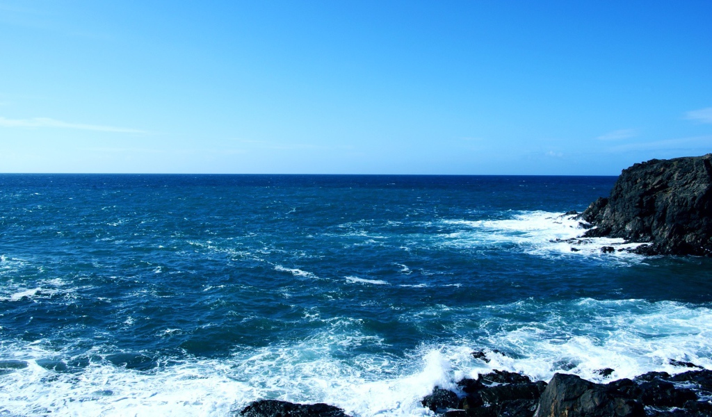 Синее море у черных камней