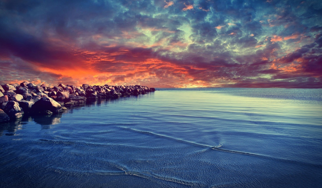 Красный закат над каменистым берегом