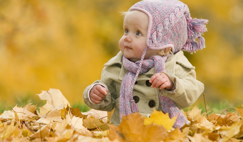 Ребенок играет осенними листьями