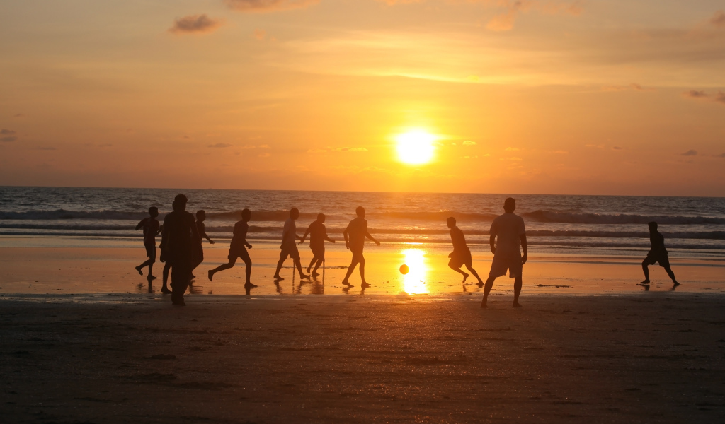 Парни играют в футбол на пляже в Гоа