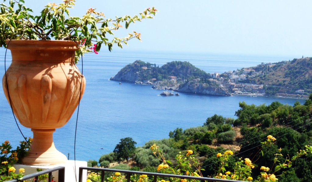 Кувшин с цветами на фоне залива на острове Сицилия, Италия