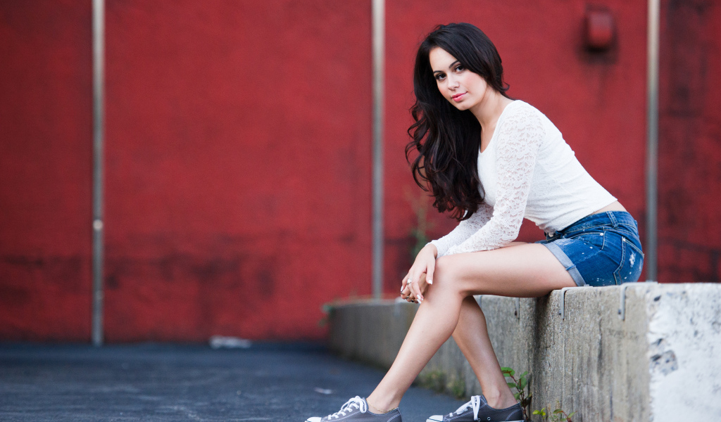 Брюнетка в кедах на бордюре