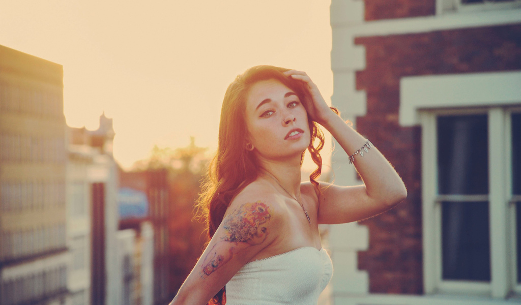 Девушка на закате с татуировкой на плече