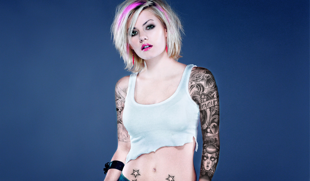 Девушка бунтарка с татуировками на руке и животе