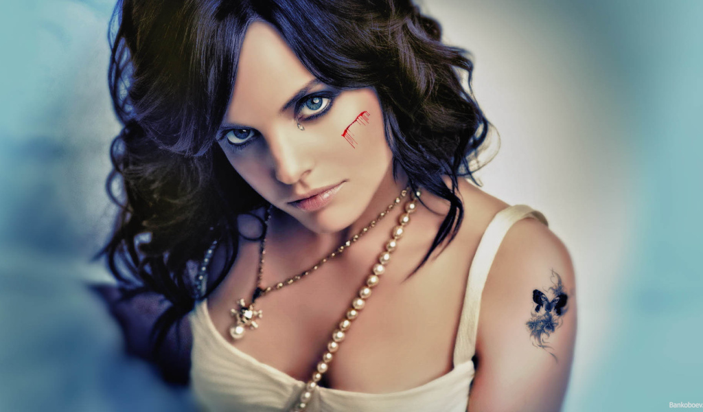 Шрам на щеке и татуировка на плече у девушки