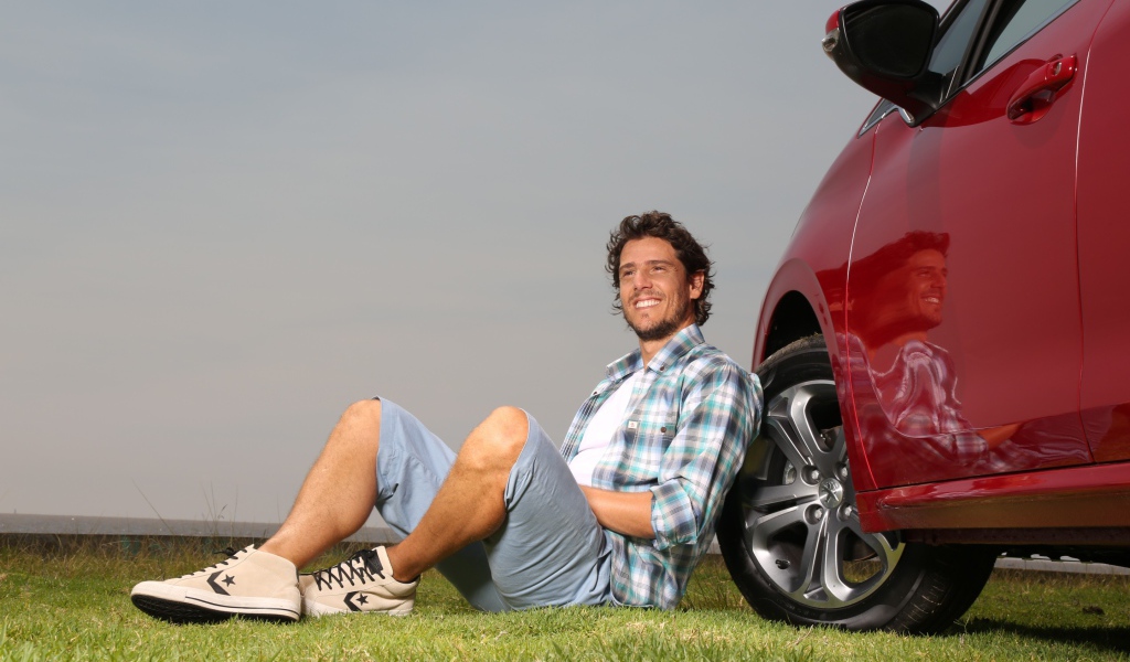 Мужчина сидит у колеса своего автомобиля