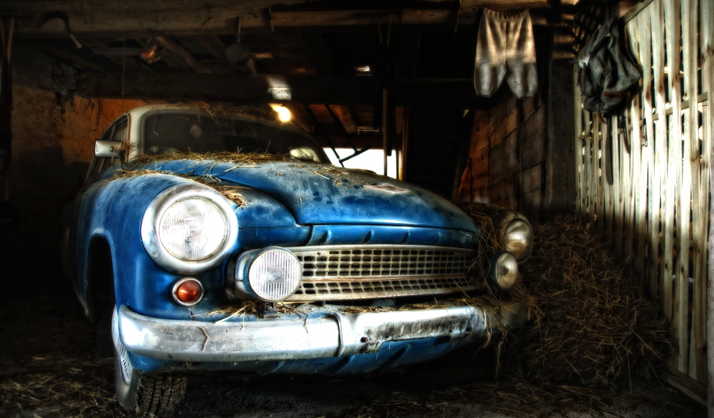 Старый автомобиль присыпан сеном в сарае