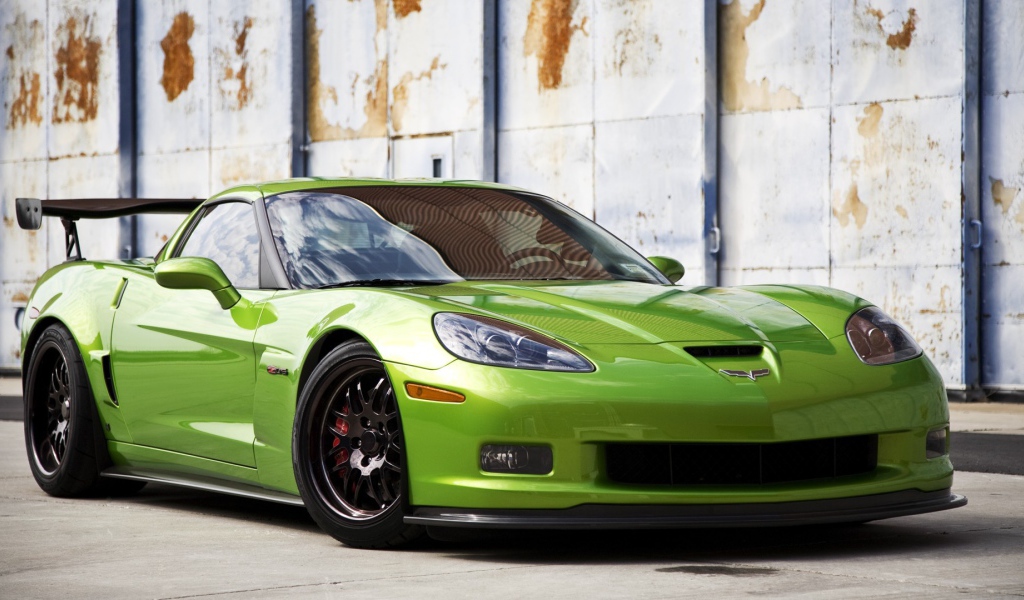 Зеленый Chevrolet Corvette на фоне стены