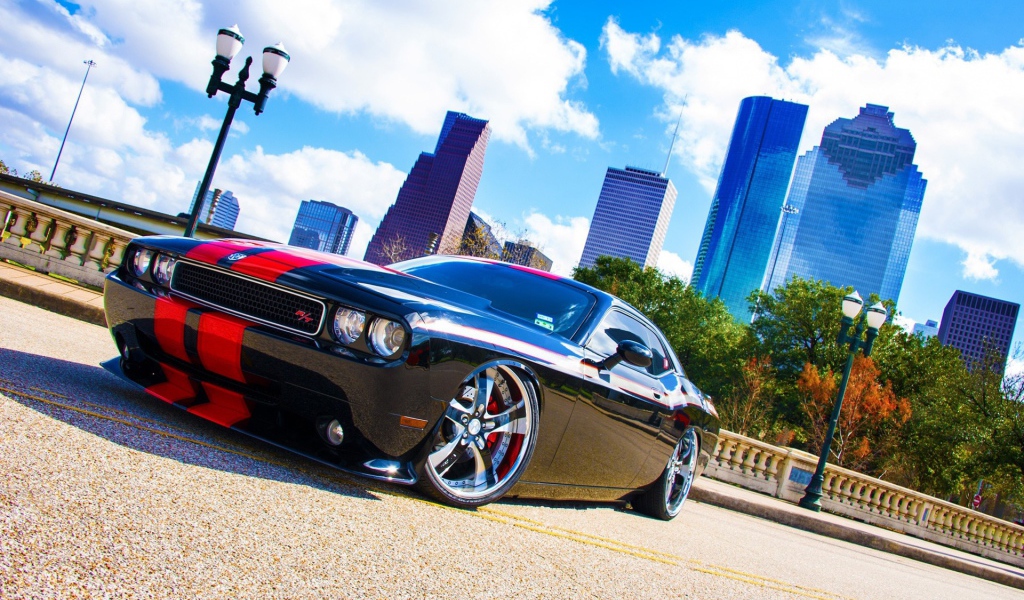 Черный Dodge Challenger с красными полосами на фоне небоскребов