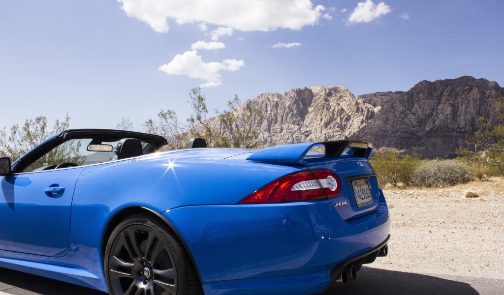 Голубой кабриолет Jaguar на фоне гор