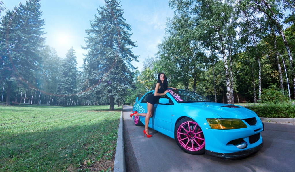 Девушка облокотилась на голубой Mitsubishi Lancer Evo X