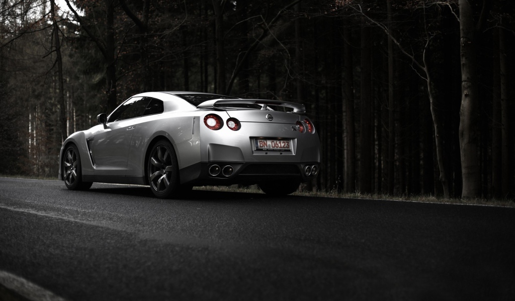 Серебристый Nissan GT-R на фоне темного леса
