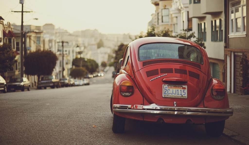 Красный Volkswagen Beetle припаркован на краю улицы