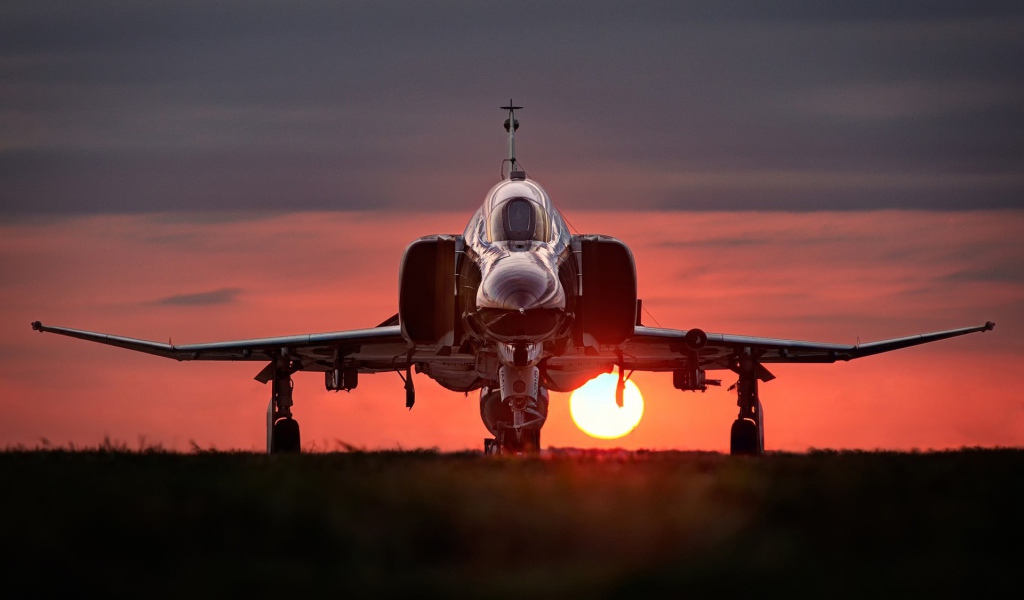 Истребитель F-4 Phantom II стоит на фоне заката