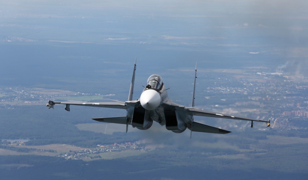 Самолет СУ-27 летит над городом