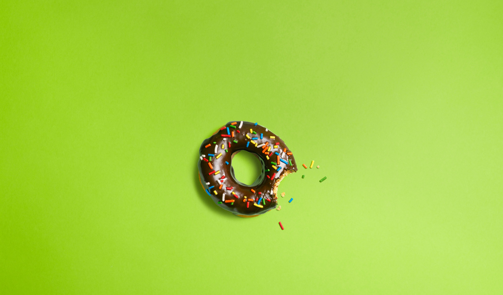 Шоколадный пончик на зеленом фоне