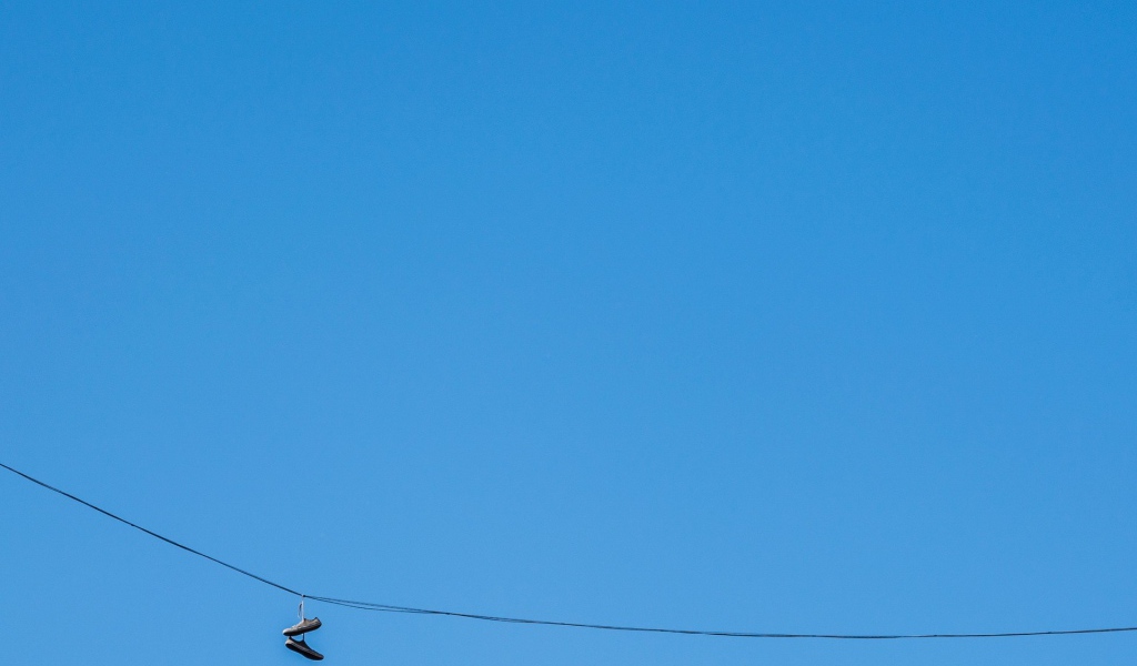 Кеды висят на проводе на фоне голубого неба