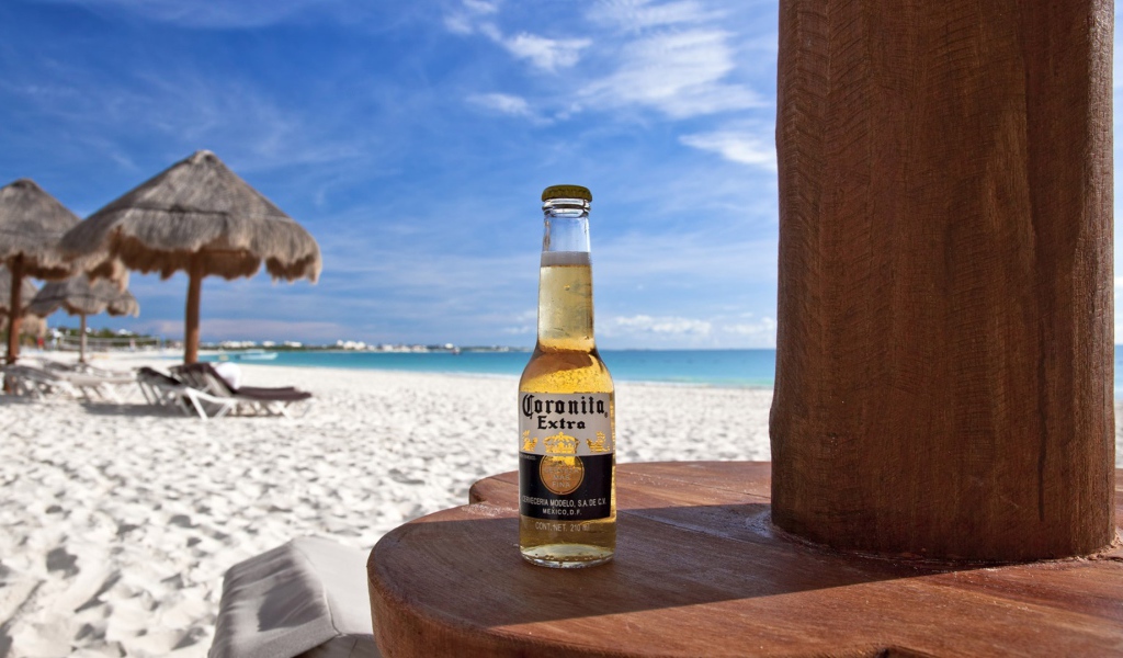 Бутылка холодного пива на столе на пляже