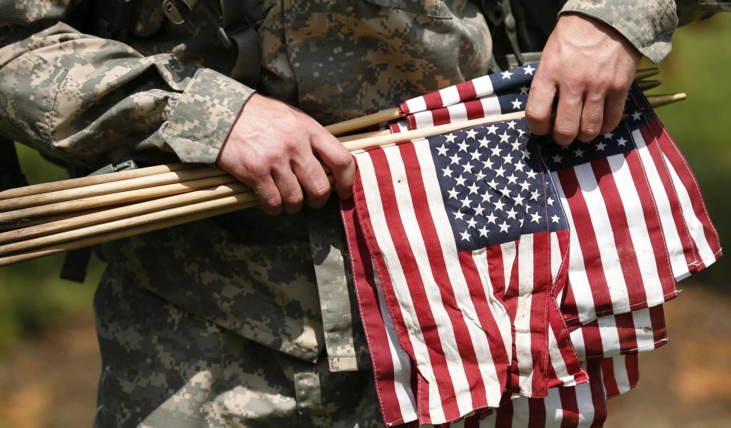 Солдат держит в руке флаги США
