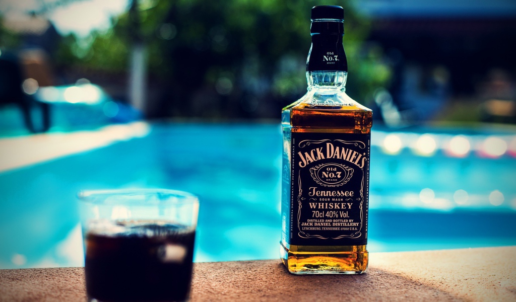 Бутылка с алкоголем на краю бассейна