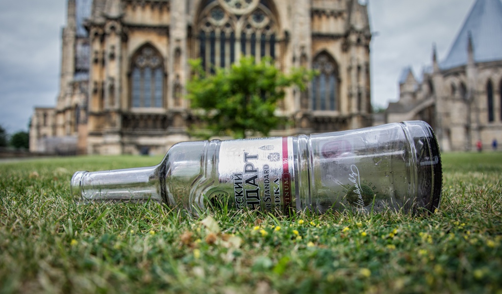 Пустая бутылка на газоне перед храмом