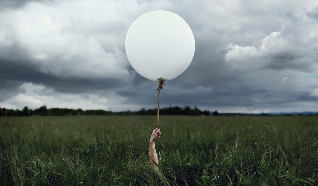 Рука с шаром среди поля