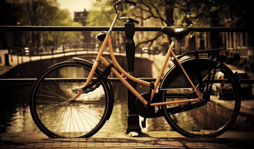 Оранжевый велосипед прислонен к перилам