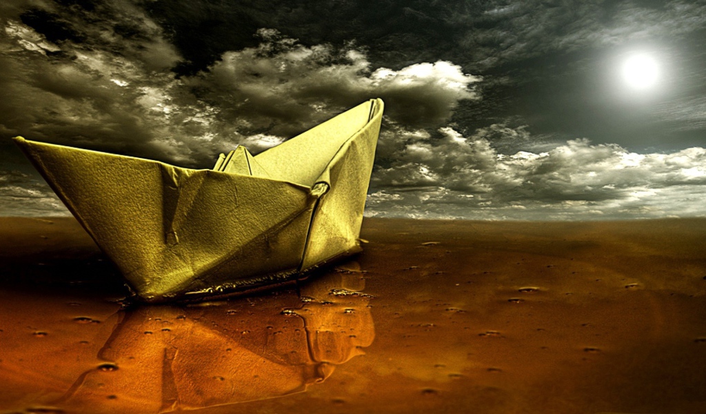 Корабль из бумаги на мокром песке