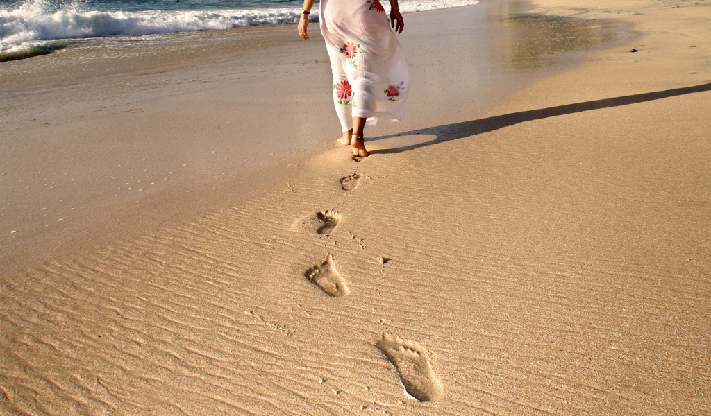 Следы босых ног на песке пляжа