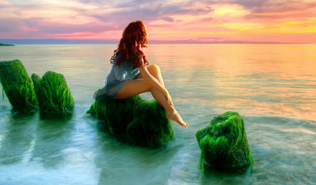 Русалка на зеленых камнях смотрит на закат