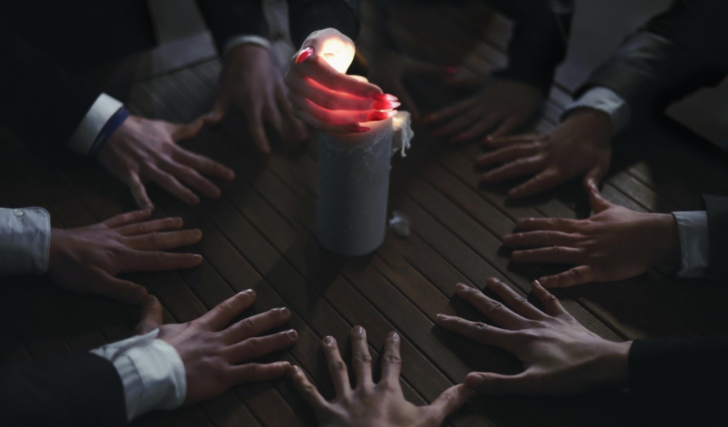 Люди вызывают духа при помощи свечи